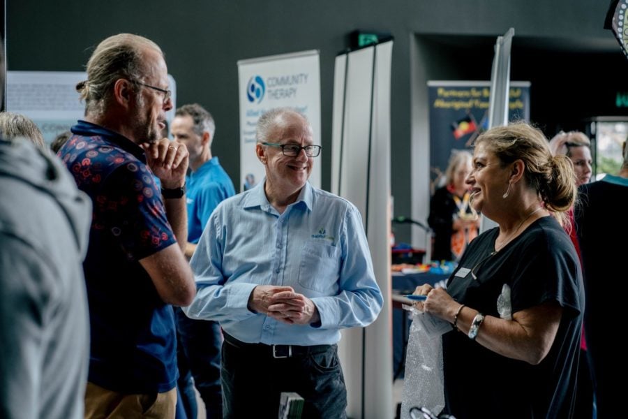 Three people engaging in a friendly conversation at a professional networking event